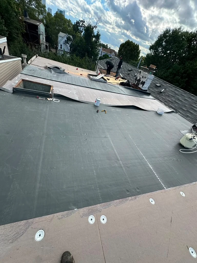 Roofing crew installing an EPDM membrane during a Jersey City flat roof replacement