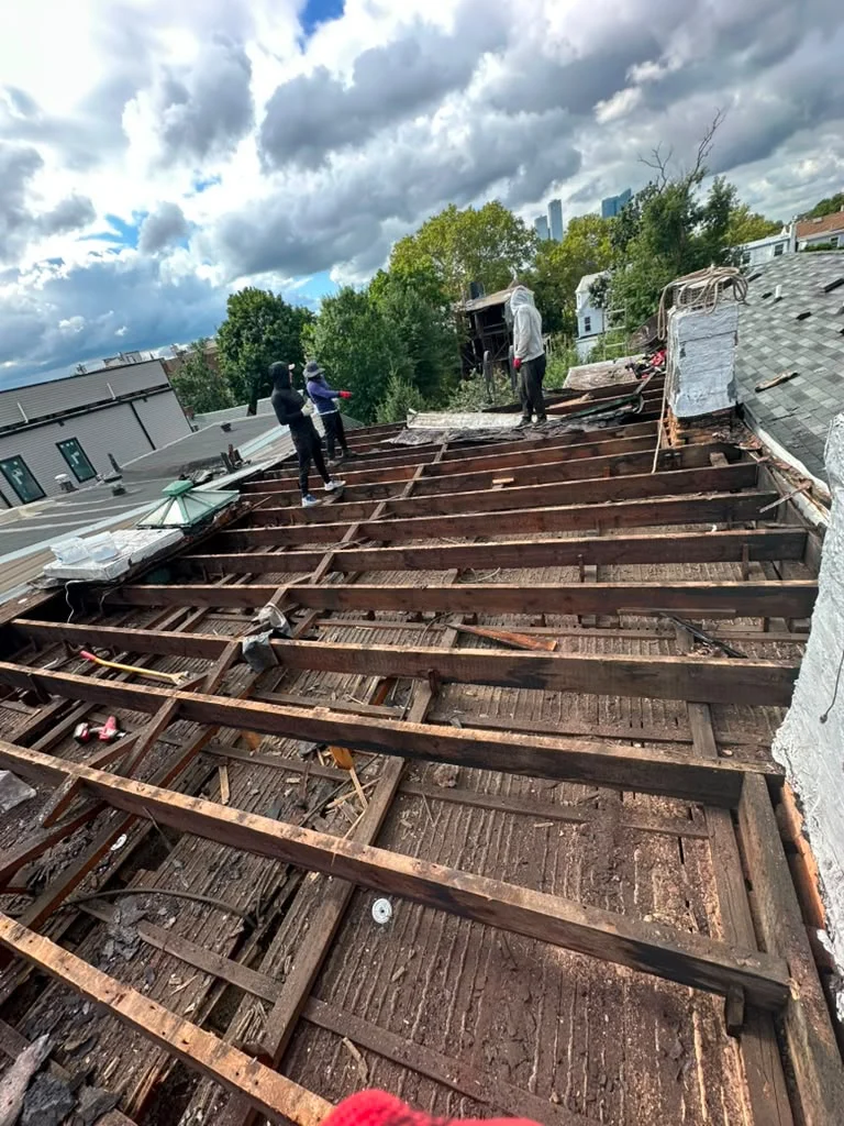 Roof tear-off exposing deteriorated framing during a Jersey City roof replacement