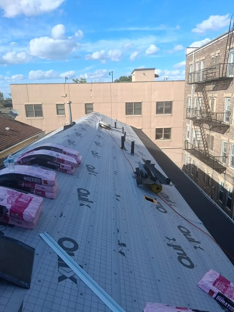 Roofing crew installing synthetic underlayment on a Jersey City pitched roof