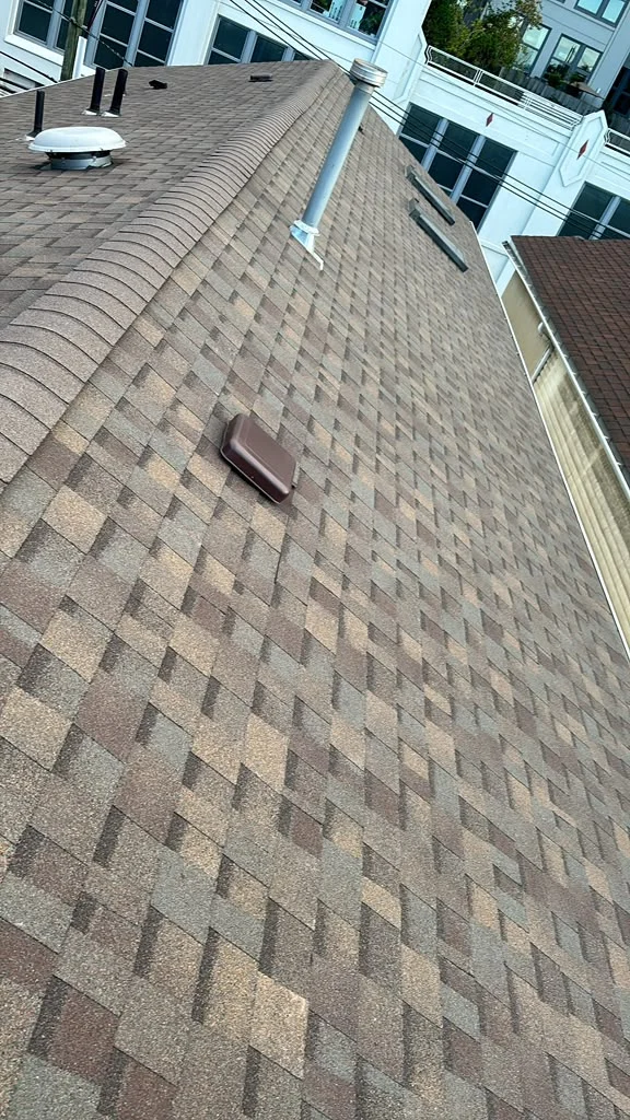 Finished brown architectural shingles with ridge caps and vent flashing in Jersey City