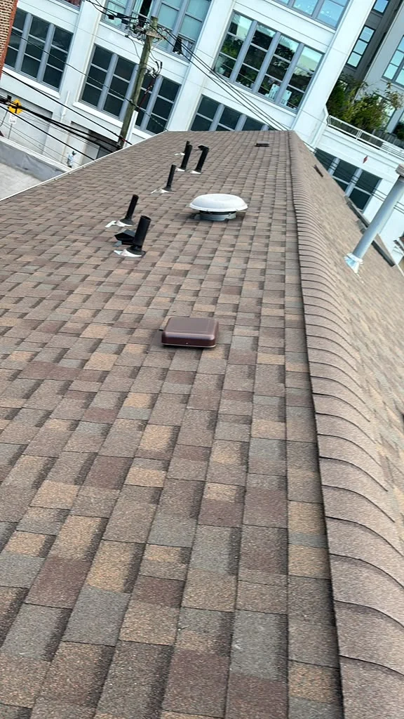 Completed architectural shingle roof with ridge and plumbing vent details in Jersey City